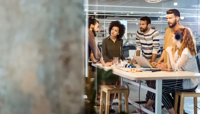 Intégration fluide avec vos équipes créatives Réunion d’équipe créative en pleine discussion autour d’une table dans un bureau moderne.
