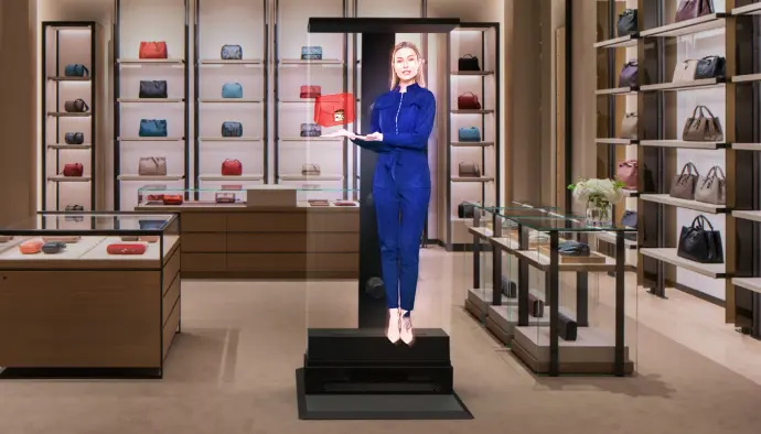 Hologramme HYPERVSN grandeur nature pour une interaction humaine saisissante Hologramme grandeur nature d’une femme présentant un sac dans une boutique de sacs à main