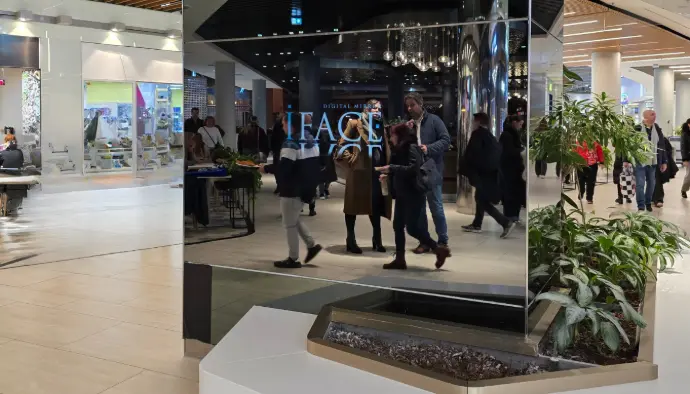 Miroir digital iFace – solution personnalisée selon vos besoins. Miroir digital iFace sur mesure installé dans un centre commercial, reflétant les passants.