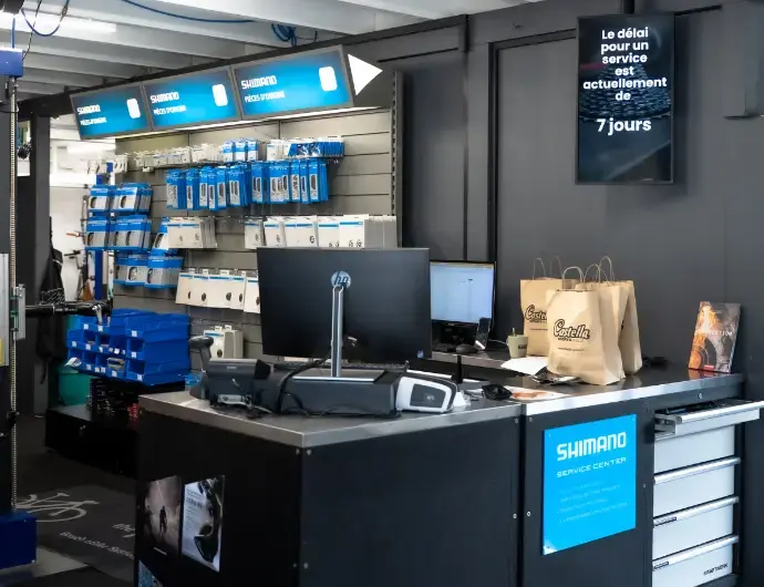 Affichage dynamique Hubgrade en magasin – renforcer l’expérience client Comptoir d’atelier de vélo avec affichage dynamique Hubgrade indiquant le délai de service
