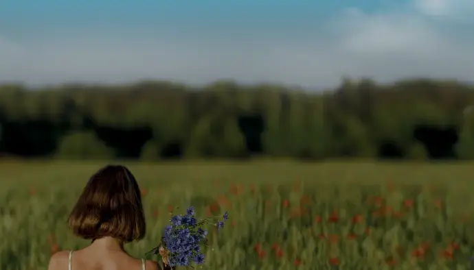 Femme tenant un bouquet de fleurs dans un champ, illustrant une expérience sensorielle unique