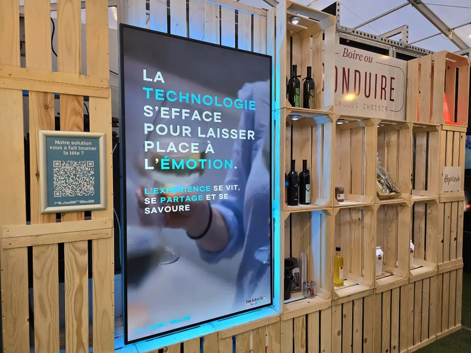 Écran d’affichage dynamique Hubgrade intégré dans une structure en bois pour le stand de la Cave Guillod au Comptoir Broyard