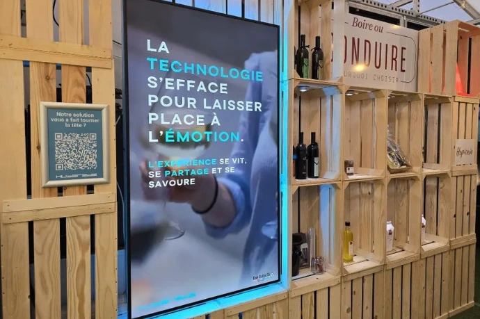 Écran d’affichage dynamique Hubgrade intégré dans une structure en bois pour le stand de la Cave Guillod au Comptoir Broyard.